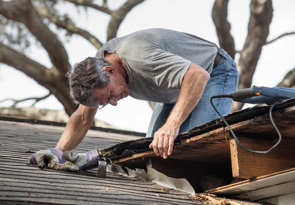 man removed his left hand glove while checking the state of a roof