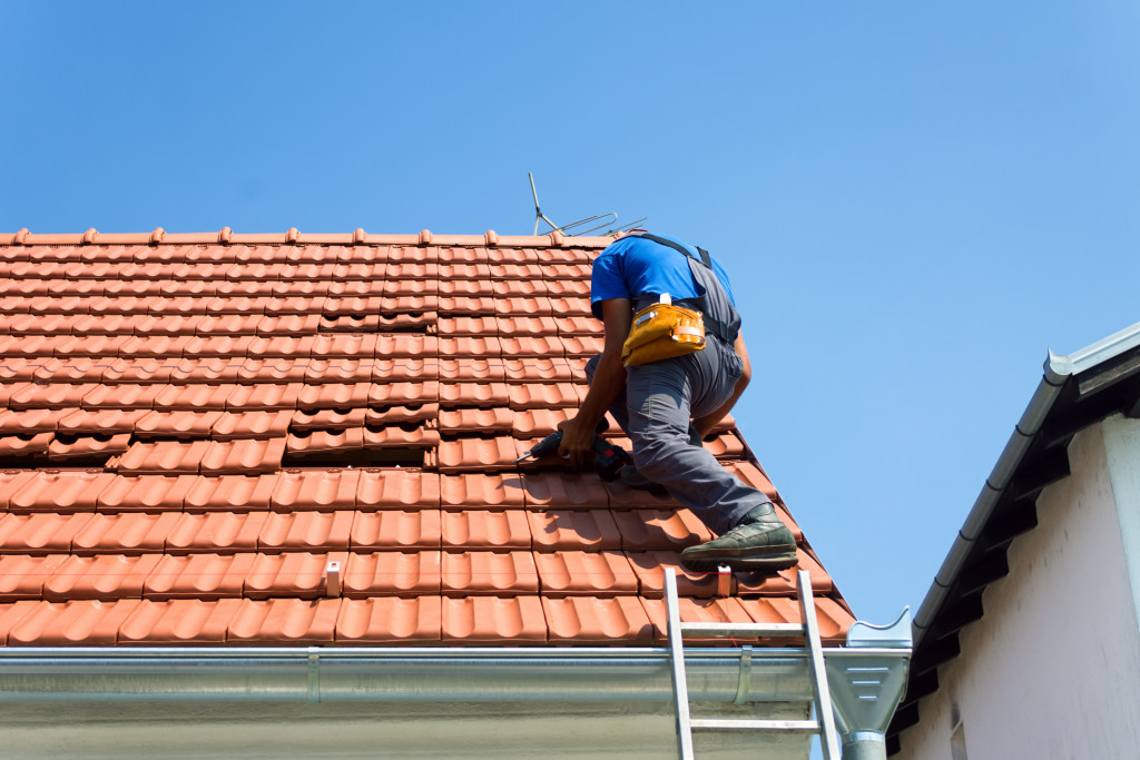 A roofer is on the roof repairing it