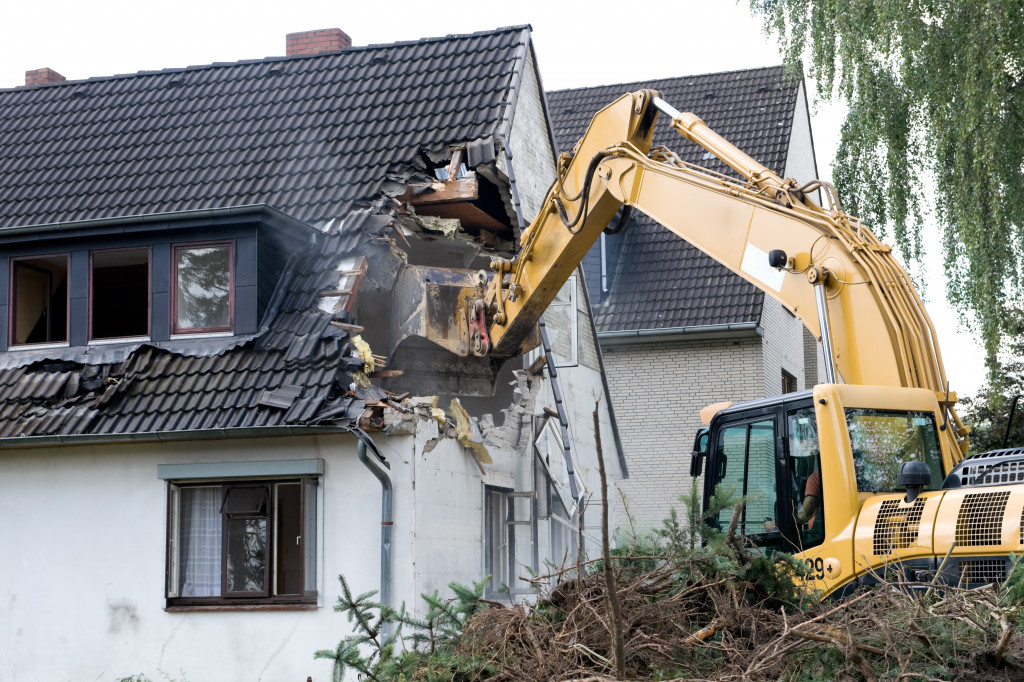 Backhoe demolishing a house