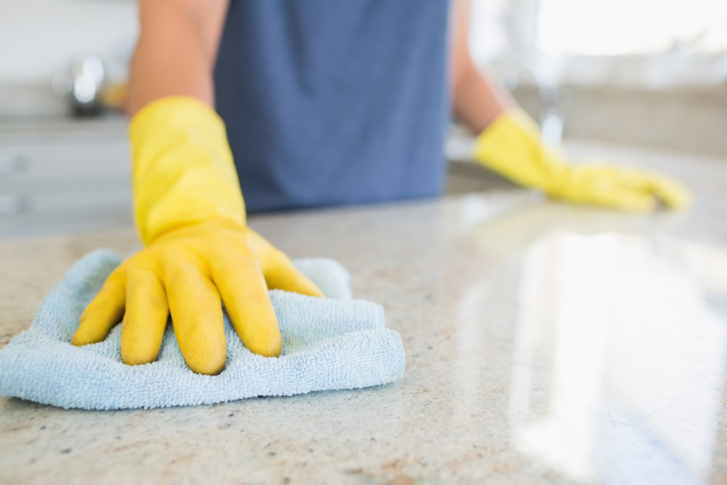 Focus on gloved hand wiping a fabric cloth over a countertop