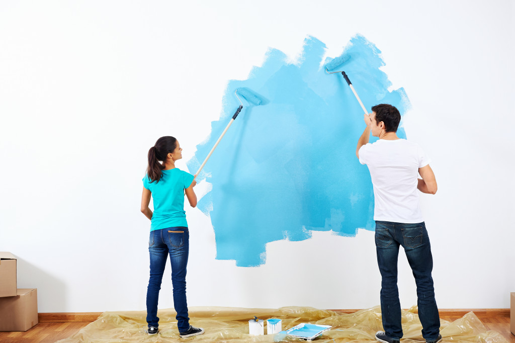 a couple painting a wall blue