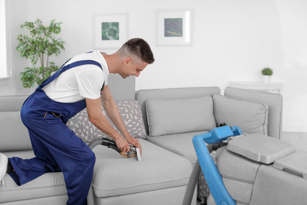 a male cleaner cleaning the sofa