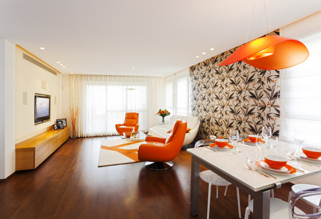 Bright home interior with orange chairs, cream walls. and orange lights.