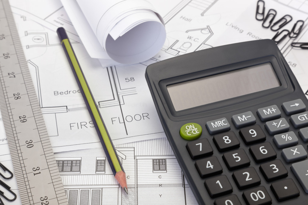 House plans with a calculator, pencil, and ruler o a table.