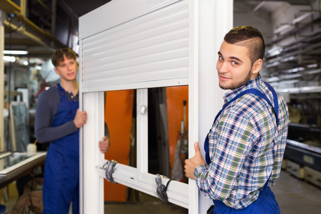 Workmen checking a window with storm shutter in a workshop.