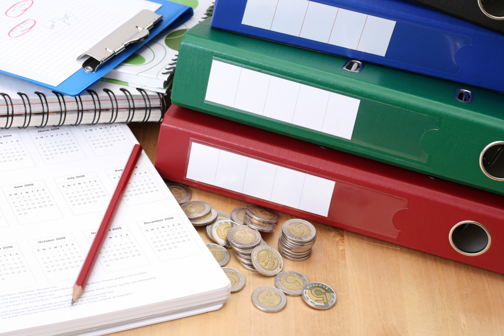 a stack of files with calendar and coins on table